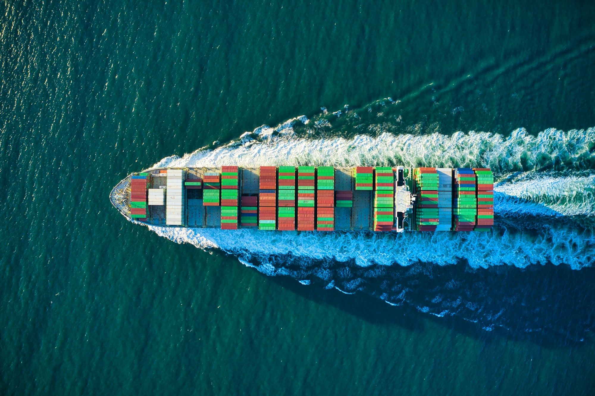 Aerial view of a container ship moving through blue ocean